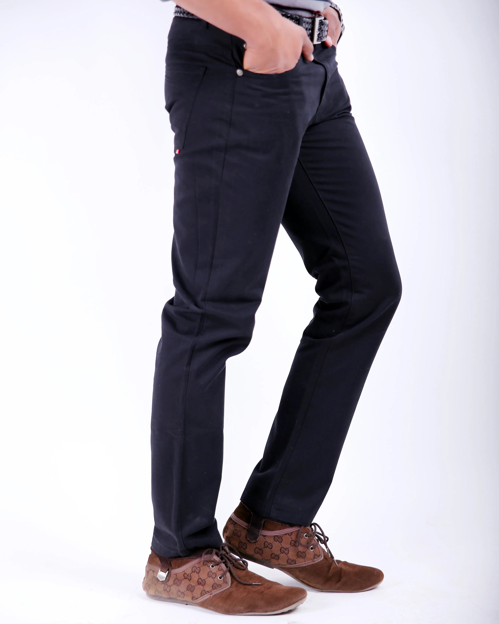 Person wearing black pants and brown shoes on a white background