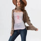 Woman wearing a brown cardigan, white t-shirt with a pink design, blue jeans, and a brown hat on a white background.