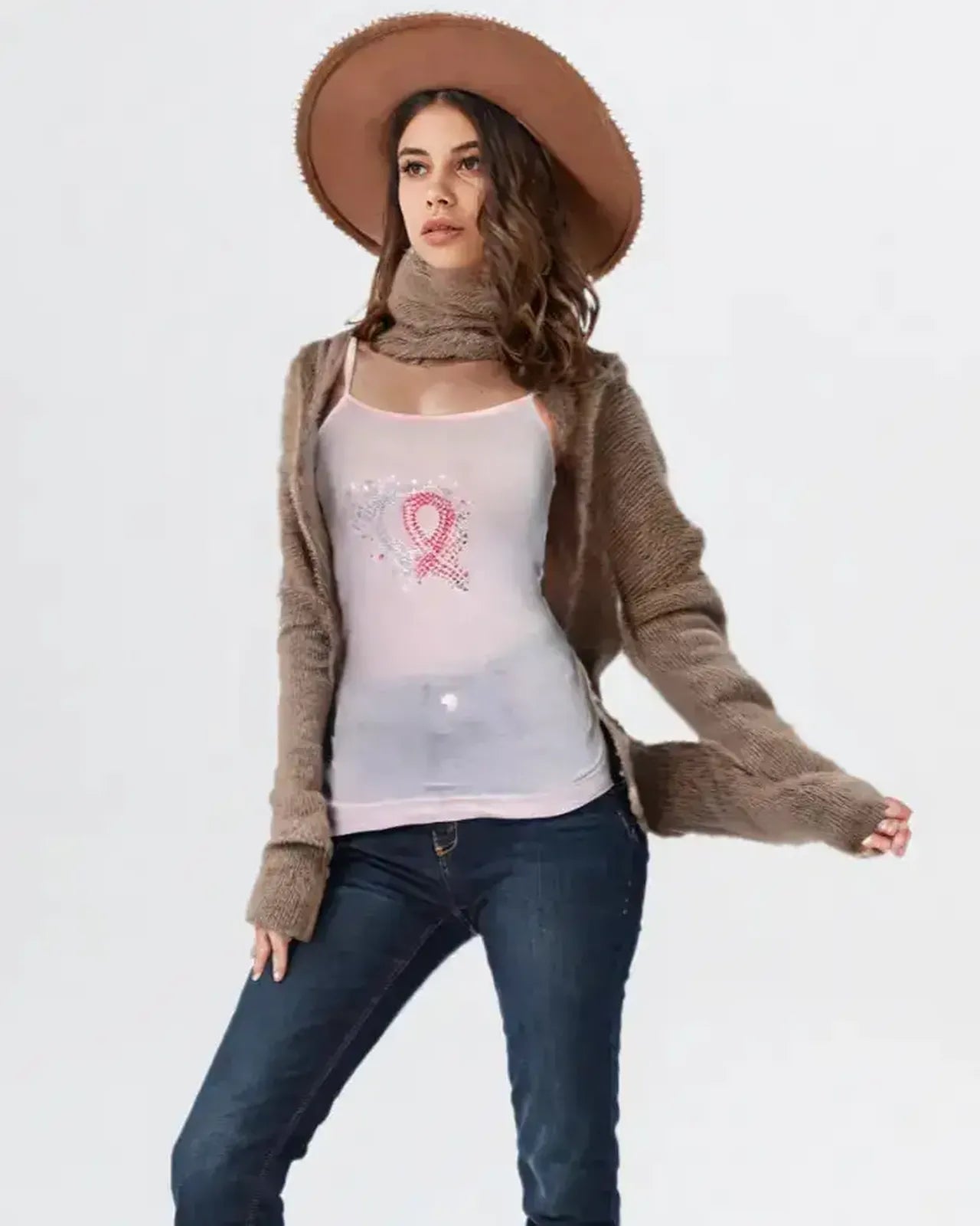 Woman wearing a brown cardigan, white t-shirt with a pink design, blue jeans, and a brown hat on a white background.