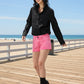 Woman wearing a black shirt and pink shorts on a white background