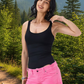 Woman wearing a black tank top and pink shorts on a white background