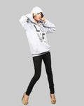 Person wearing a white hoodie with text and black pants on a gray background