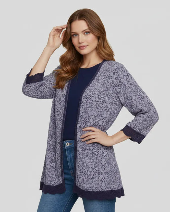 Woman wearing a patterned cardigan over a plain top and jeans on a light gray background