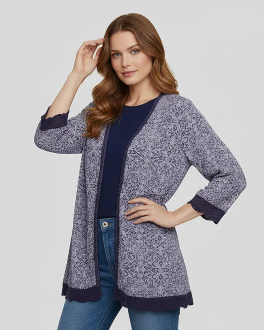 Woman wearing a patterned cardigan over a plain top and jeans on a light gray background