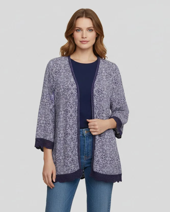 Woman wearing a patterned cardigan over a plain top and jeans on a light gray background