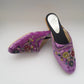 Purple embroidered mules on a light gray background