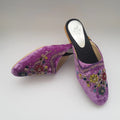 Purple embroidered mules on a light gray background