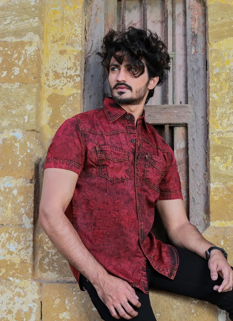 Man wearing a red denim shirt against a rustic background