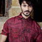Man wearing a red denim shirt against a rustic background