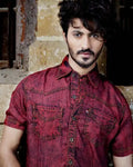 Man wearing a red denim shirt against a rustic background