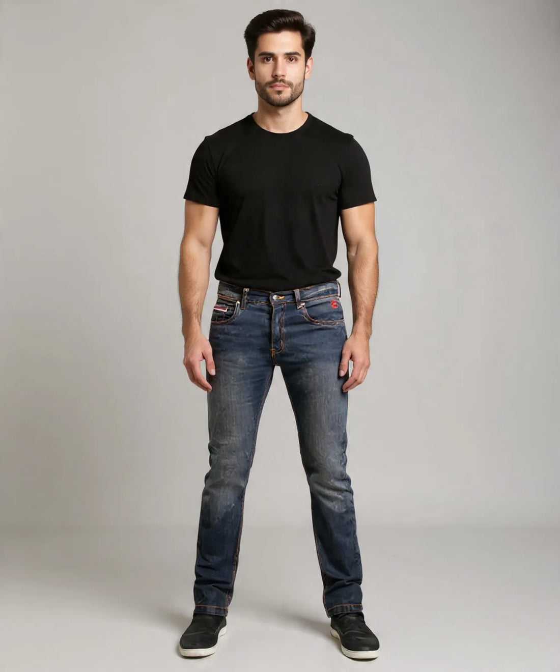 Man wearing a black t-shirt and blue jeans on a gray background