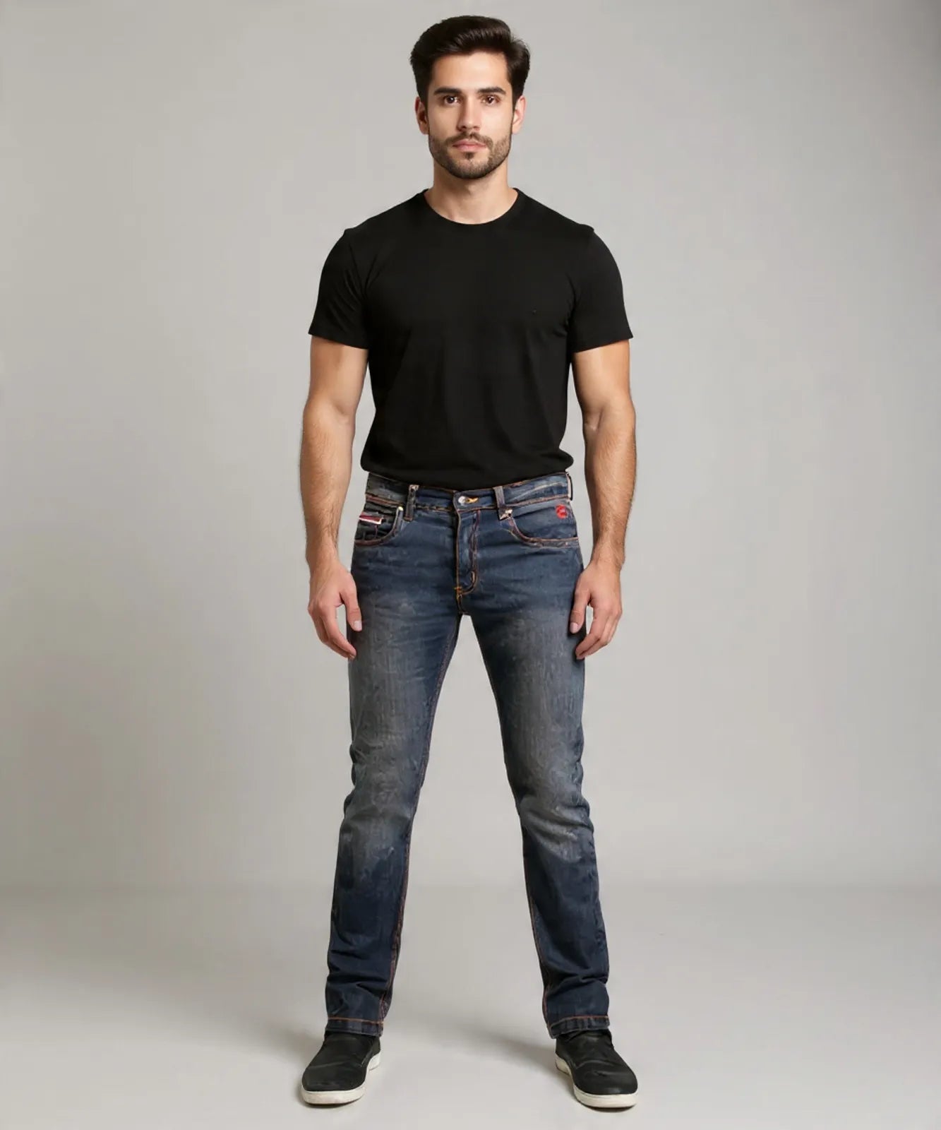Man wearing a black t-shirt and blue jeans on a gray background