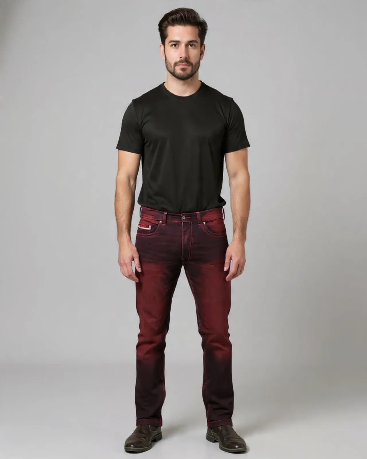 Man wearing a black t-shirt and maroon jeans against a gray background