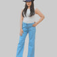 Woman wearing a white sleeveless top and blue jeans with a dark hat on a white background