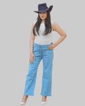 Woman wearing a white sleeveless top and blue jeans with a dark hat on a white background