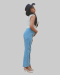 Woman wearing a white sleeveless top and blue jeans with a dark hat on a white background