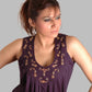 Woman wearing a purple sleeveless top with floral embroidery on a gray background