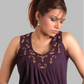Woman wearing a purple sleeveless top with floral embroidery on a gray background