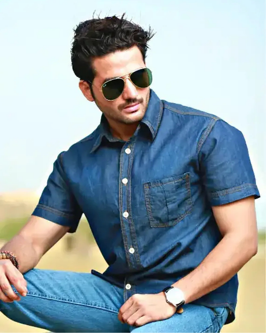 Man wearing sunglasses and a blue shirt with a blurred background