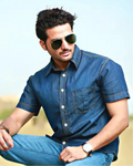 Man wearing a blue denim shirt and sunglasses with a clear sky background