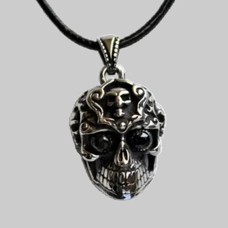 Skull pendant necklace on a black cord against a white background