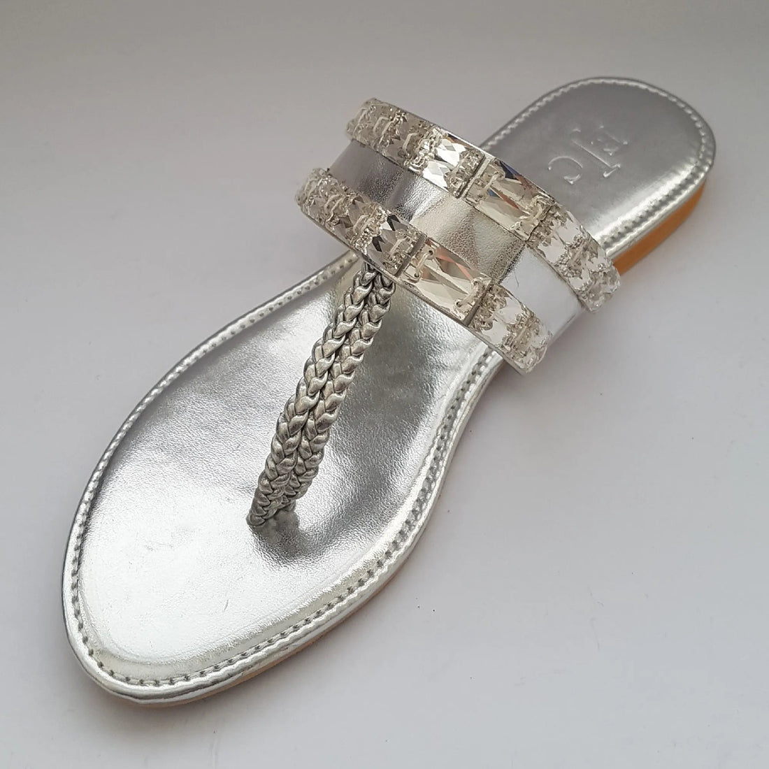 Silver sandal with embellishments on a light gray background
