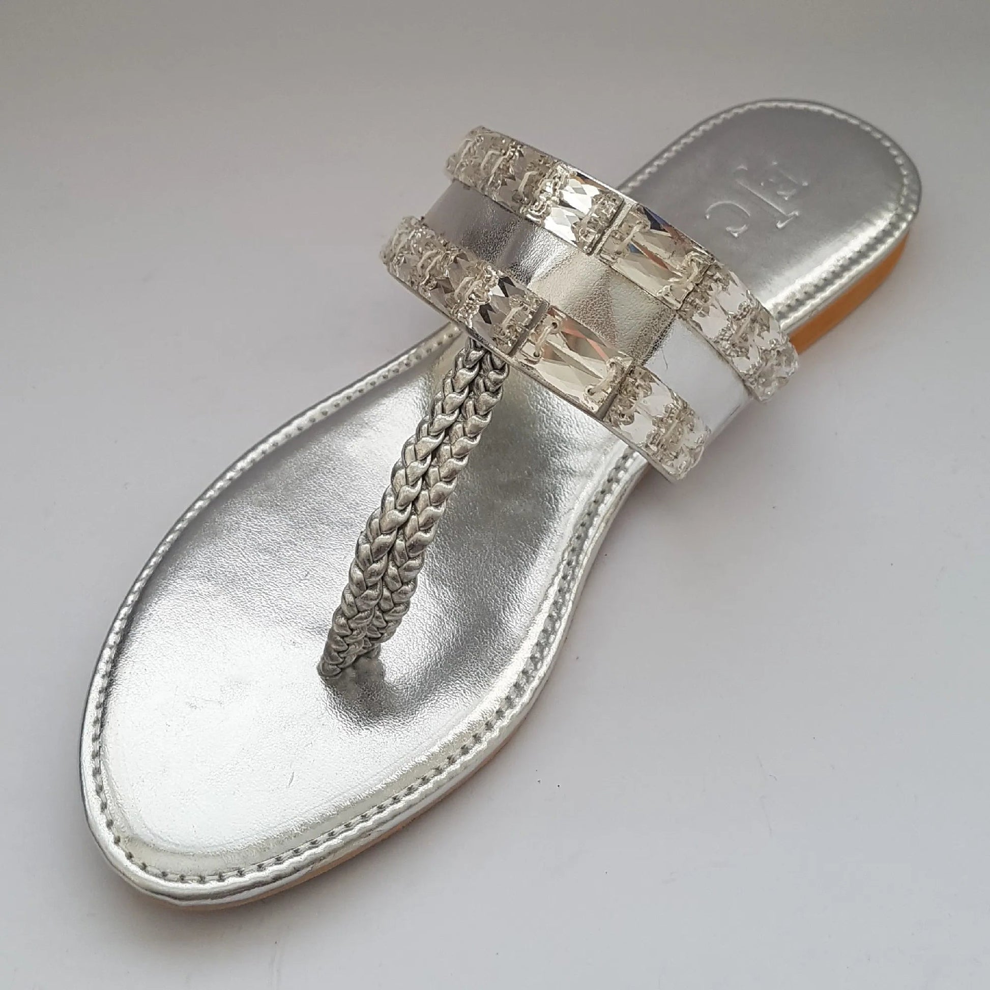 Silver sandal with chain detail on a light gray background