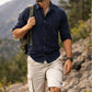 Man hiking outdoors with mountains and trees in the background
