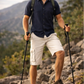 Man hiking on a mountain trail with trekking poles and a backpack.