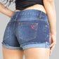 Person wearing blue denim shorts with a visible brand logo on a plain background