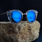 Sunglasses with blue lenses on a rock against a dark background
