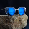 Sunglasses with blue lenses on a rock against a dark background