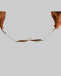 Two hands holding a delicate necklace on a white background