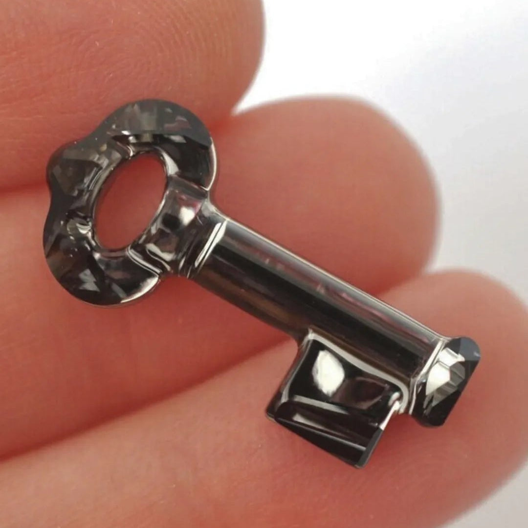 Close-up of a silver key held between fingers with a blurred background