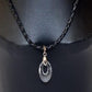 A Swarovski Helix Pendant displayed on a mannequin, featuring a clear, drop-shaped crystal pendant suspended from a black braided leather string.