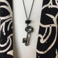 Necklace with a key pendant on a black and white patterned background