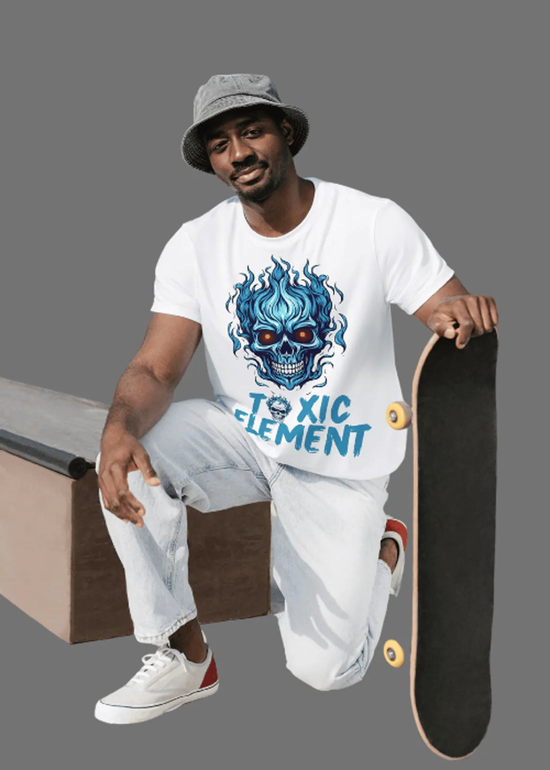 Man sitting on a skateboard ramp holding a skateboard, wearing a white t-shirt with a graphic design.