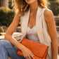 Woman holding an tan clutch bag outdoors