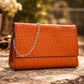 Tan clutch bag with a chain strap on a stone surface with a blurred natural background