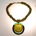 Green beaded necklace with a circular pendant on a light background