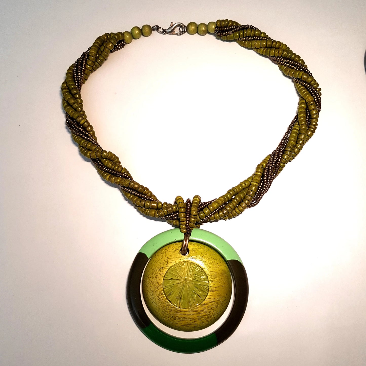 Green beaded necklace with a circular pendant on a light background