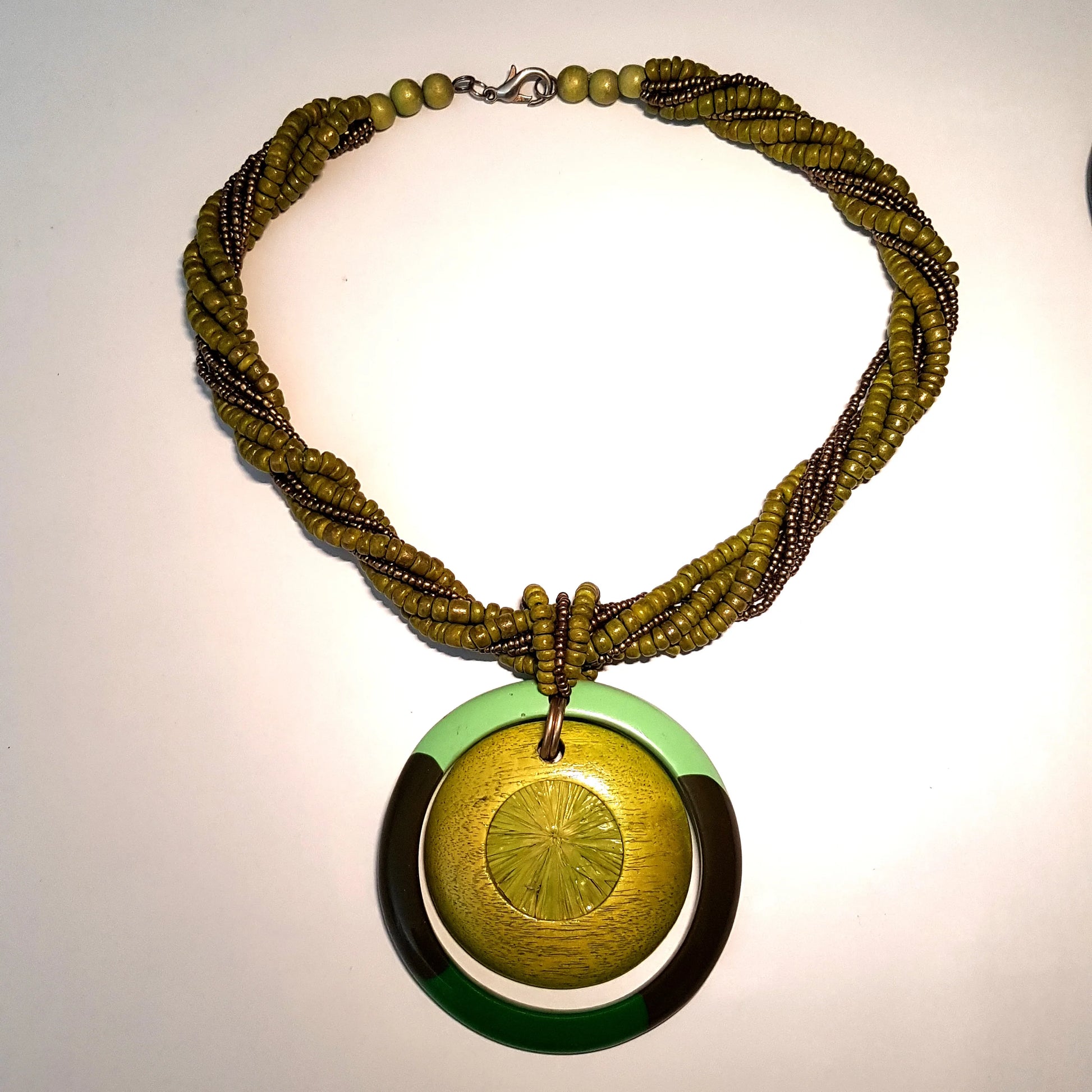 Green beaded necklace with a circular pendant on a light background