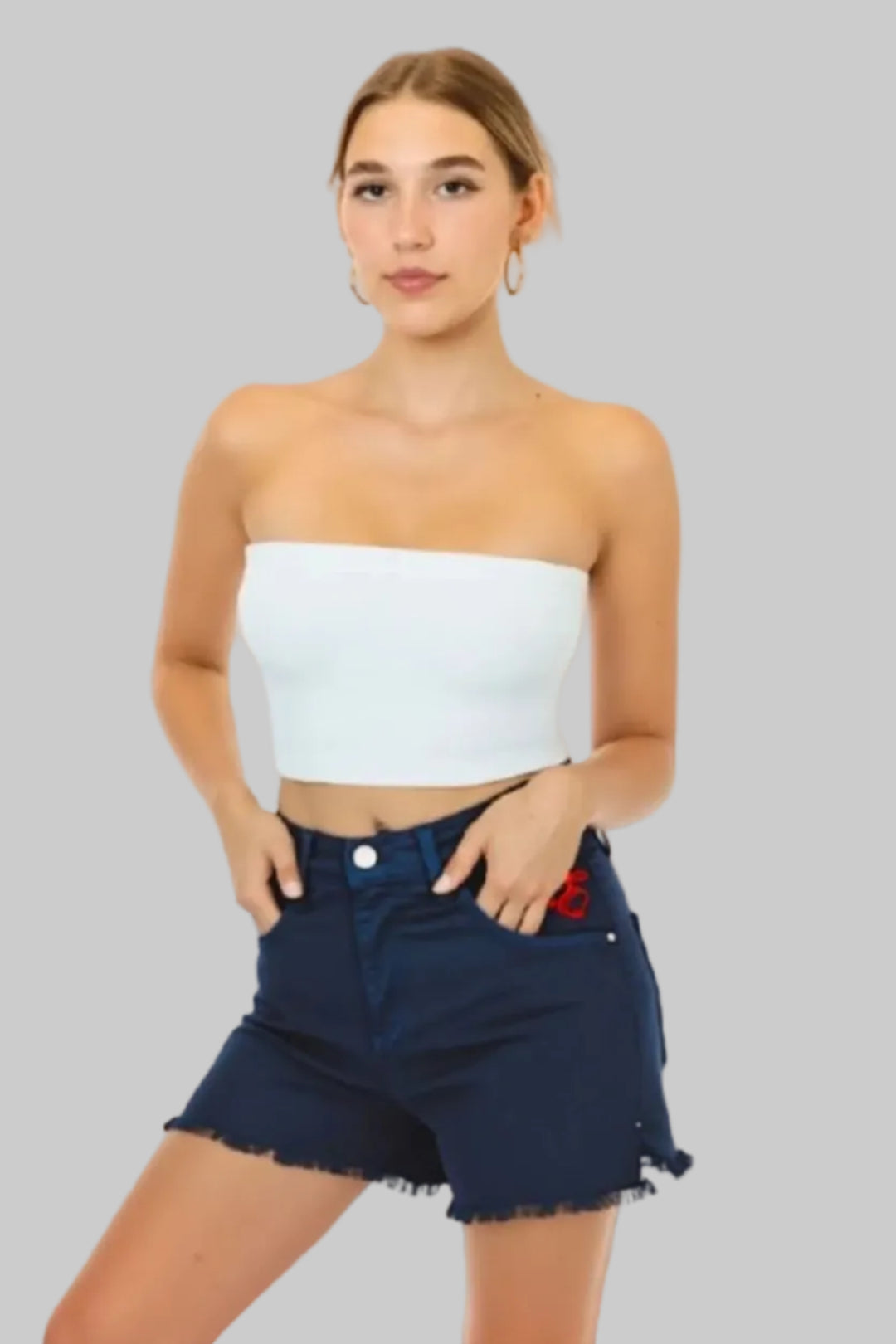 Woman wearing a white strapless top and navy denim shorts on a beige background with Element Jeans Co branding.