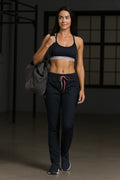 Woman in athletic wear holding a bag in a dark room