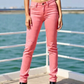 Person wearing pink jeans standing by a waterfront.