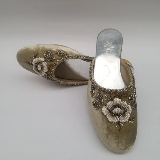 Pair of embellished shoes with floral designs on a light gray background