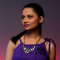 Woman wearing a purple dress with a necklace against a gradient background