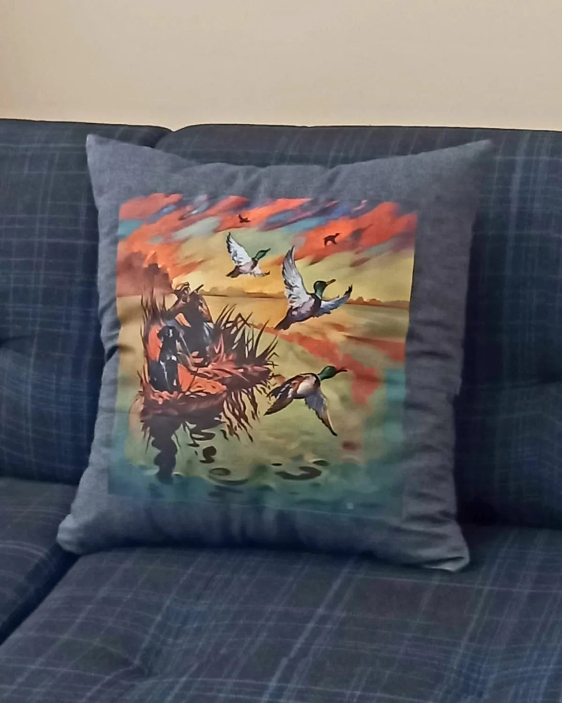 Decorative pillow with a hunting scene on a blue couch