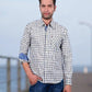 Man standing on a wooden pier wearing a checkered shirt and jeans.