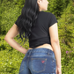 Person wearing blue denim shorts with a visible brand logo on a plain background